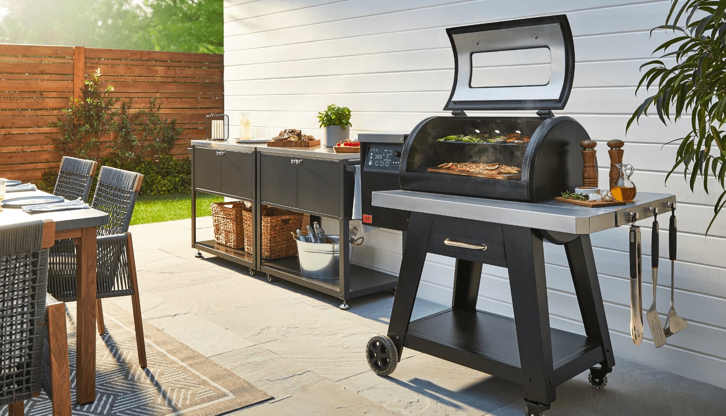 Food cooking on an outdoor grill in a backyard filled with BBQ accessories and a patio dining set.