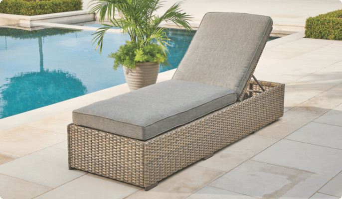 Une chaise longue CANVAS Bala installée sur une terrasse au bord de la piscine avec une plante en pot. 