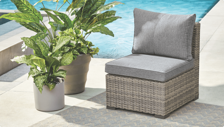 Un fauteuil sans accoudoirs CANVAS Bala installé sur une terrasse au bord de la piscine avec des plantes en pot. 
