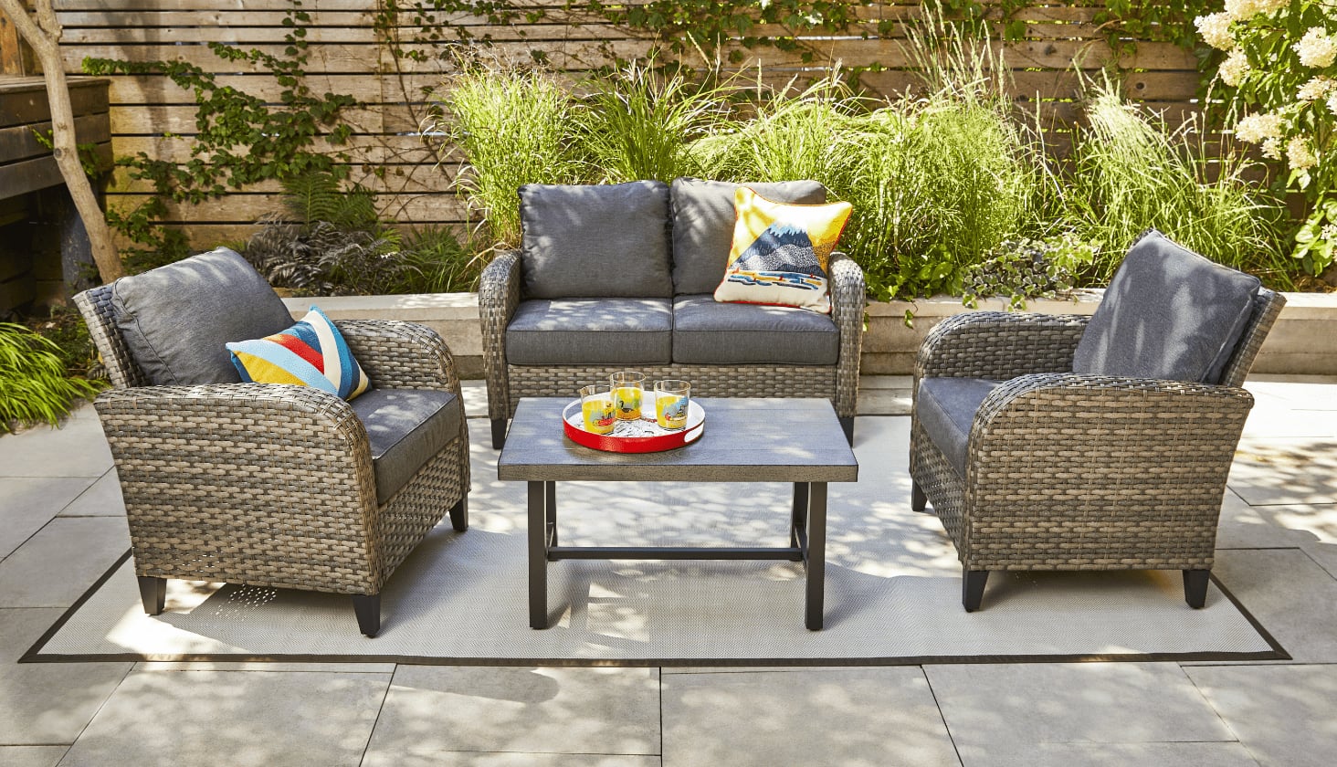 A CANVAS Breton Loveseat, two armchairs and a coffee table arranged in a garden patio.