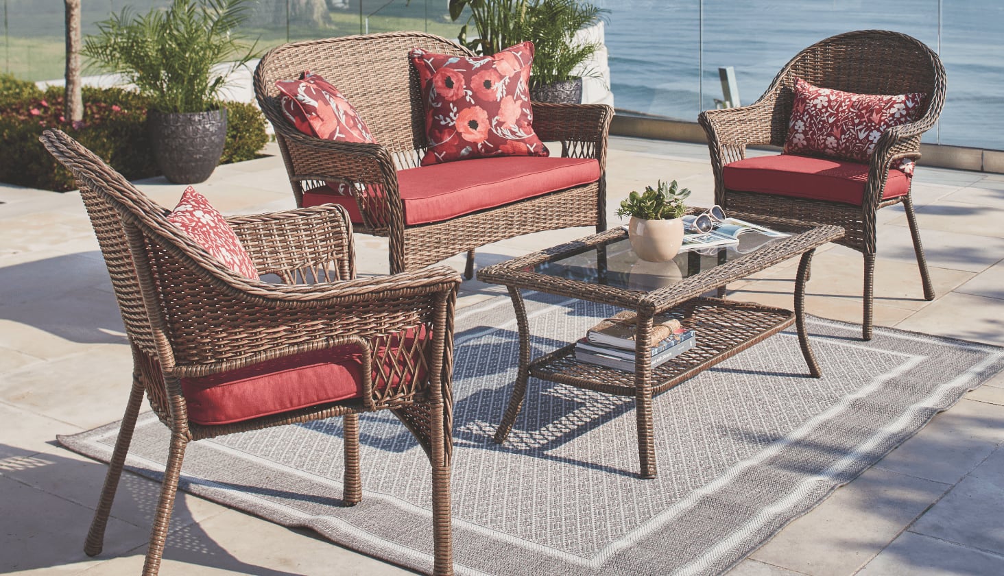 Une causeuse, des fauteuils et une table basse de la collection CANVAS Canterbury sur un patio au bord de l’eau. 