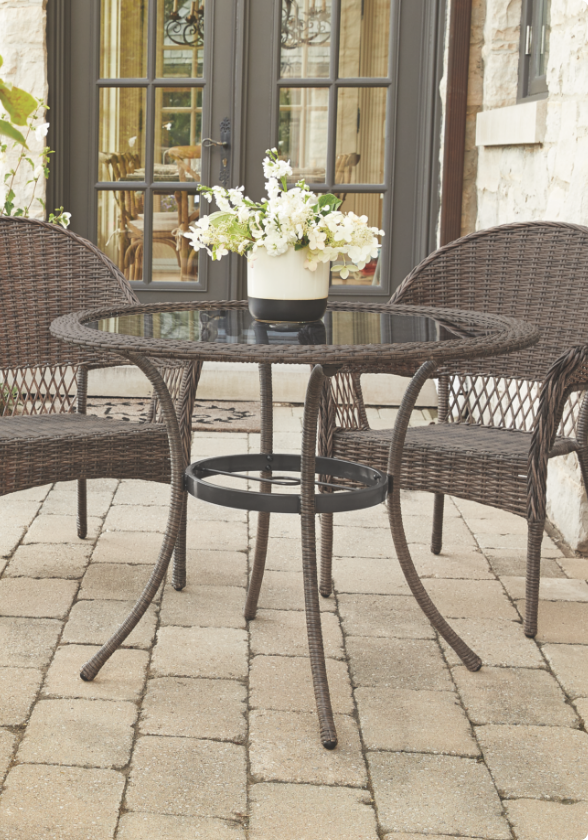 A CANVAS Canterbury Dining Table with two dining chairs on a patio.