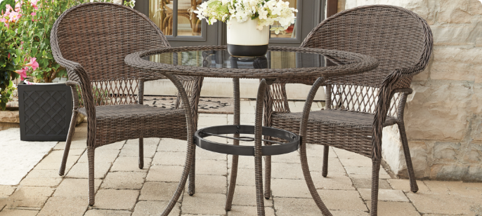 A CANVAS Canterbury Dining Table with two dining chairs on a patio.