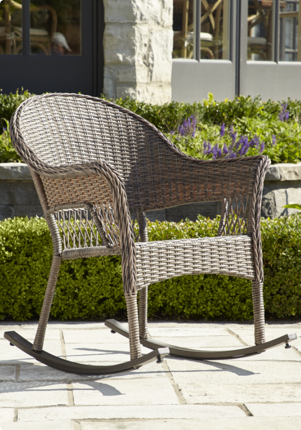 A CANVAS Canterbury Wicker Rocking Chair on a patio.   