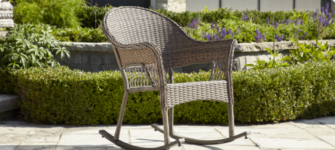 A CANVAS Canterbury Wicker Rocking Chair on a patio.   