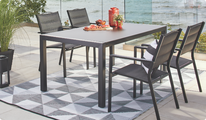 A CANVAS Mercier Dining Table and chairs on a waterfront patio.
