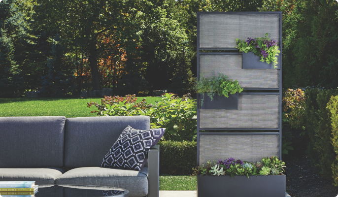 CANVAS Mercier Privacy Screen planter with leafy plants next to a sofa. 