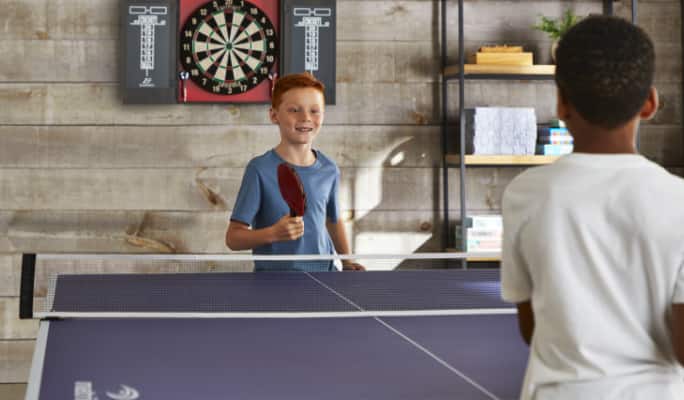 Two children playing ping pong at a blue Matrix 4000 tennis table.
