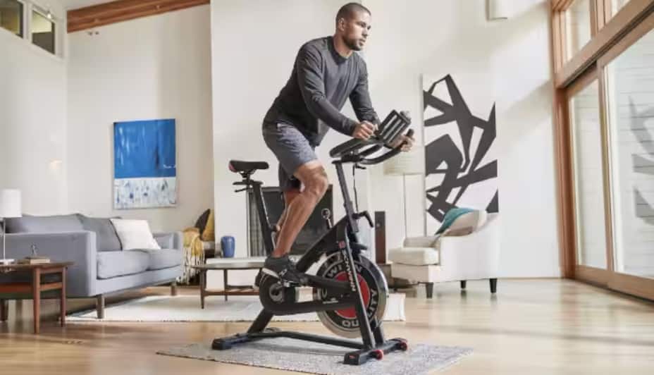 Une personne utilise un vélo d'exercice dans son salon  