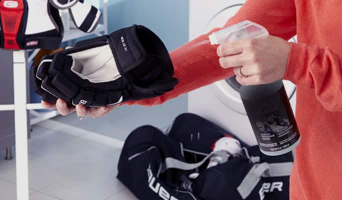 Une personne nettoyant des gants de hockey  