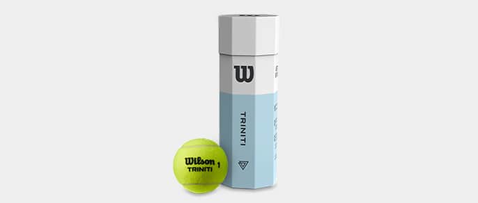Une balle de tennis Wilson Triniti à côté de son emballage octogonal en papier.