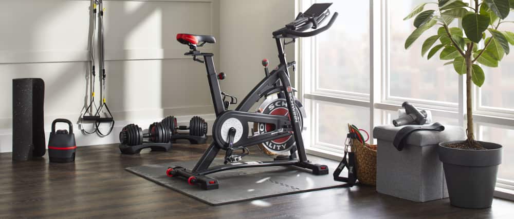 An exercise bike, dumbbells, and accessories in the corner of a condominium room.