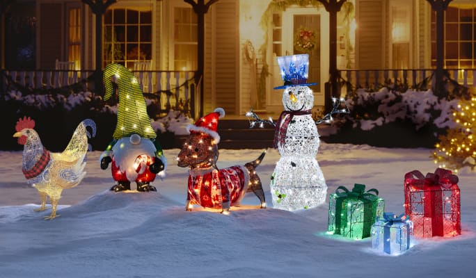 Chicken, snowman and gift Christmas figures lit up on a snowy lawn