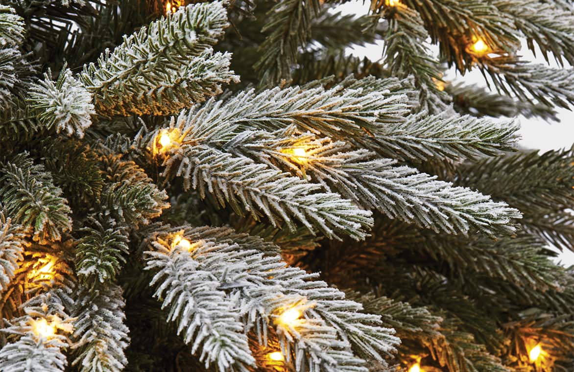 Branches d’un arbre de Noël artificiel illuminé et floqué. 