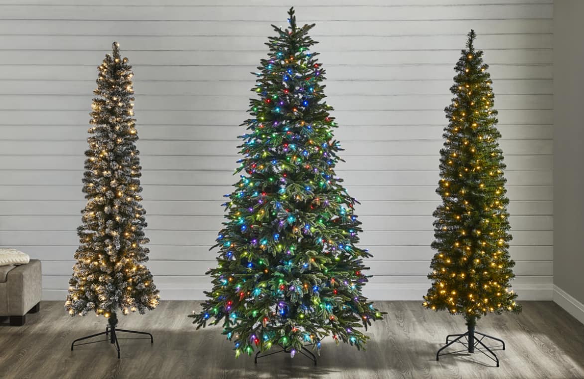 Two slim pre-lit Christmas trees on either side of a full pre-lit Christmas Tree.