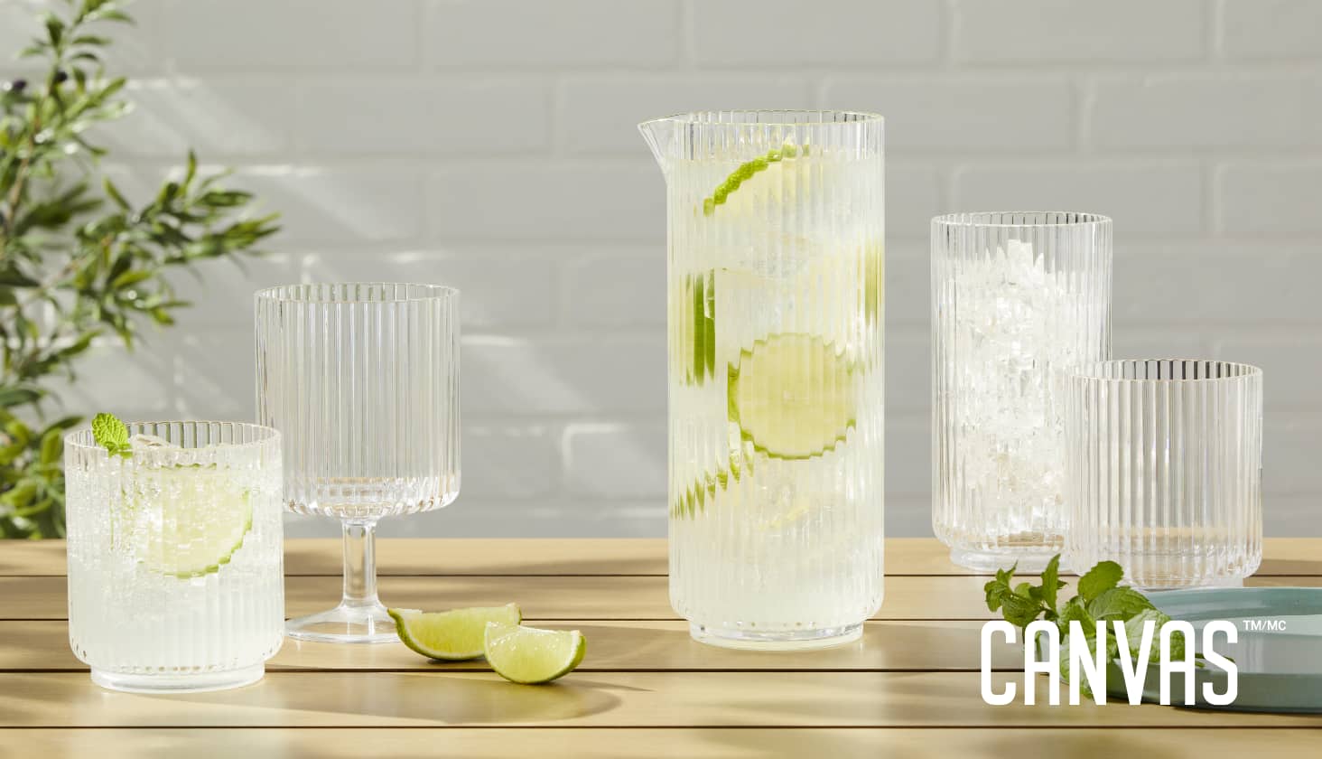 An assortment of ribbed CANVAS Tides Glassware on a table with lime slices, water and ice. 