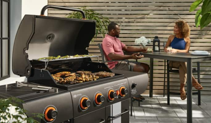 Meat cooking on a Master Chef Turismo Grill on a patio. 