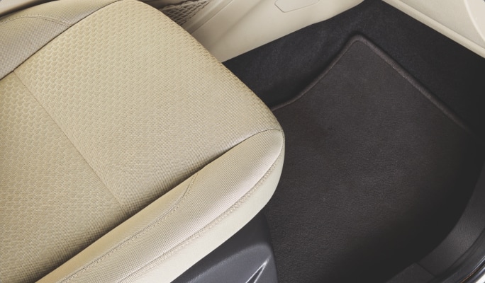 A cream-coloured car seat and black car mat.