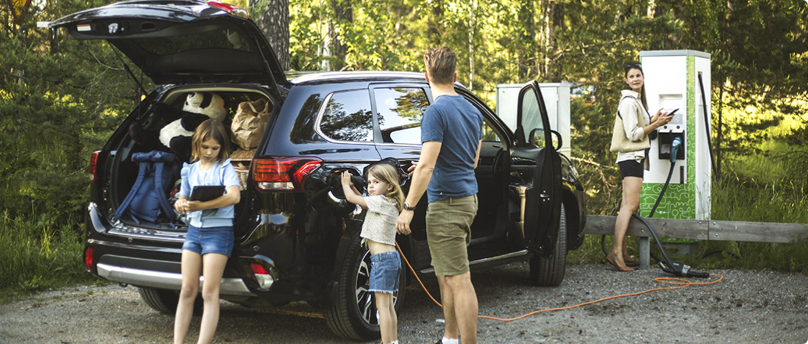 A family uses a charging point to recharge their electric crossover SUV.