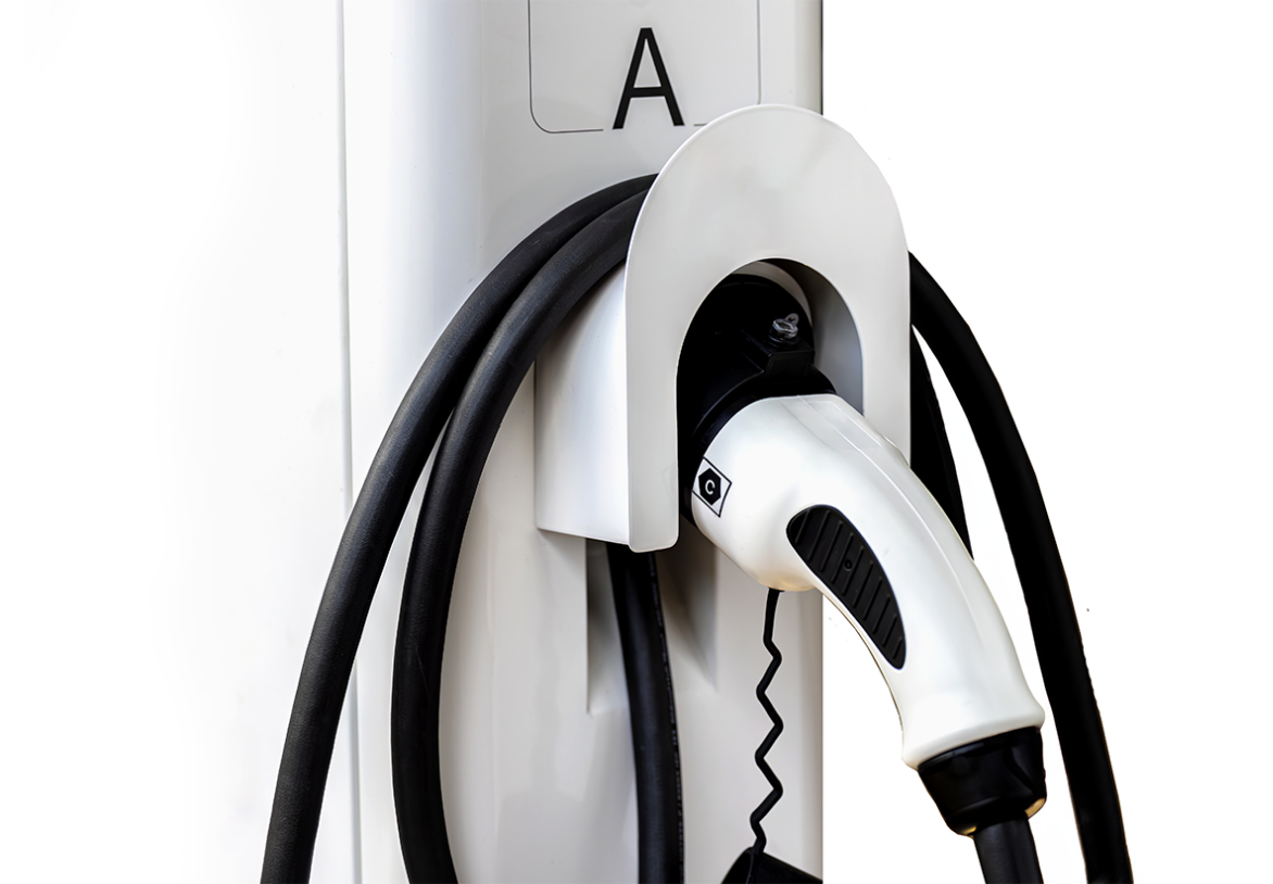 Detail of a coiled charging cable and connector at an EV charging station.