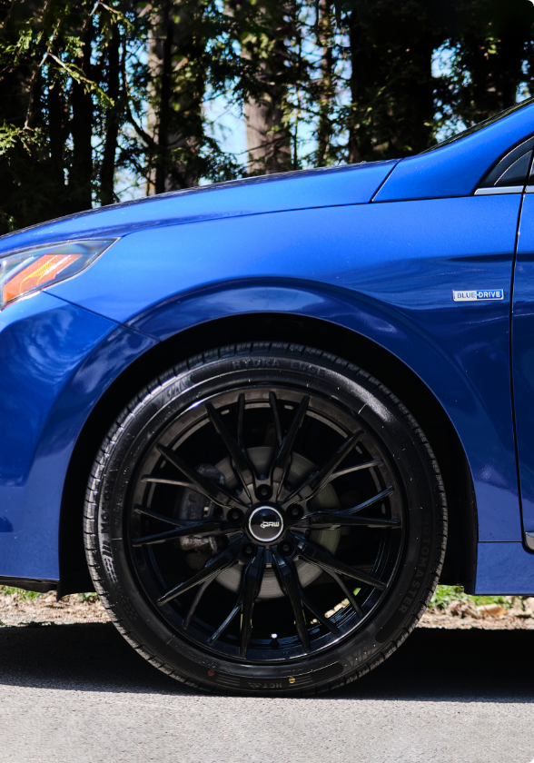 A  MotoMaster Hydra Edge tire on a blue car in an outdoor setting. 