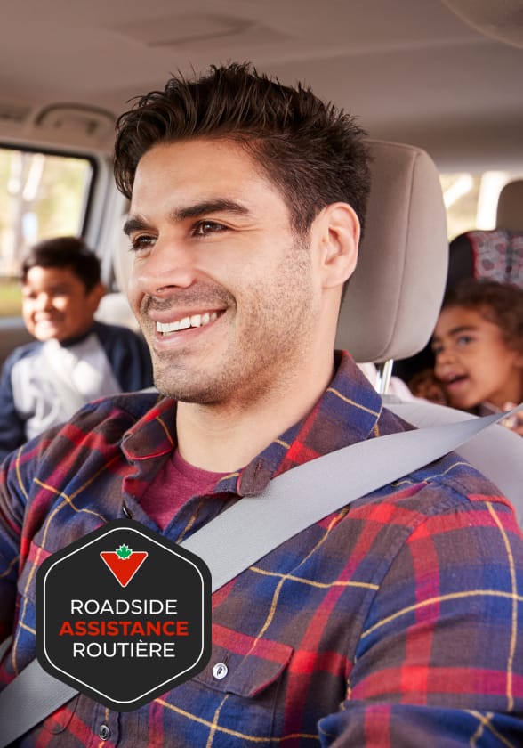 Un homme au volant d'une voiture tandis que des enfants sourient sur le siège arrière.