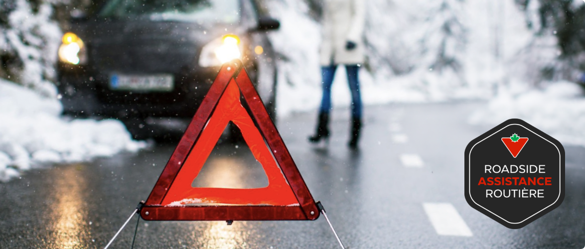 A red emergency triangle on a road near a car stuck in snow.