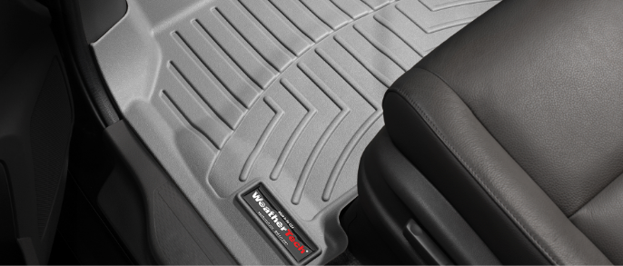 A light grey WeatherTech floor mat lines the driver’s-side footwell of a car with a black interior.