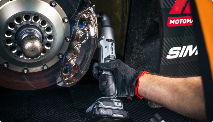 A person uses a MAXIMUM 20V Right Angle Impact Wrench on a car’s wheel.