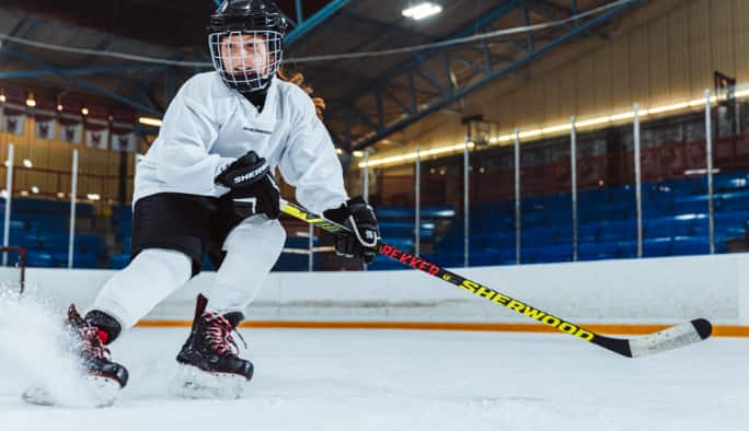 A child plays hockey on an indoor rink.