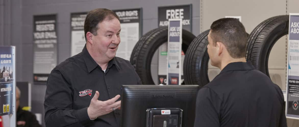 Un employé du centre-auto Canadian Tire discute avec un client.