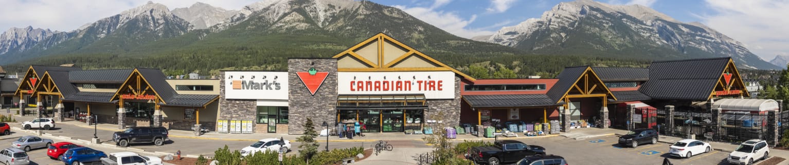 Un magasin Canadian Tire et un magasin Mark’s devant un paysage montagneux à Canmore, en Alberta.