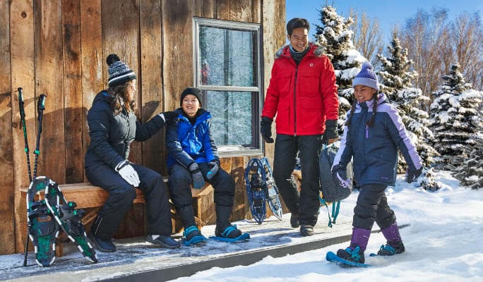 Une famille en vêtements d’hiver se prépare pour une randonnée en raquettes.