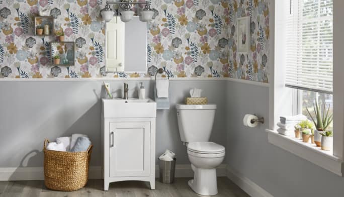 Une salle de bain en gris avec un panier tressé, un meuble de toilette et d'autres articles de la collection CANVAS Creston.