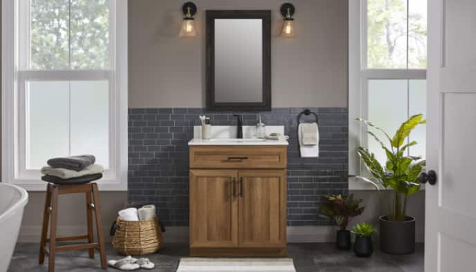 Une salle de bain en taupe et gris avec meuble-lavabo, tabouret en bois, quincaillerie noire mate et d'autres articles de la collection CANVAS Danville.