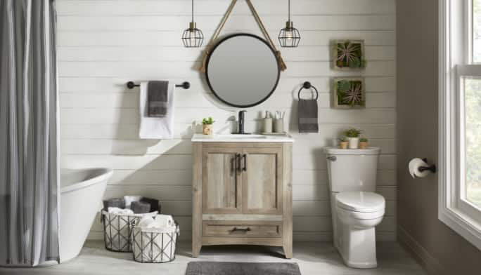 Une salle de bain en blanc avec toilettes, meuble-lavabo en chêne patiné, luminaires suspendus et d'autres articles de la collection CANVAS Wellington.