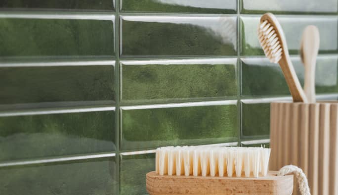 Des carreaux verts autoadhésifs peler et coller sur le mur d'une salle de bain.