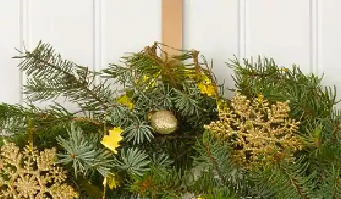 Une couronne de Noël accrochée à une porte avec un crochet en laiton. 