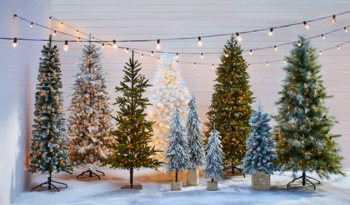 Une rangée d’arbres de Noël artificiels de différents styles et tailles.