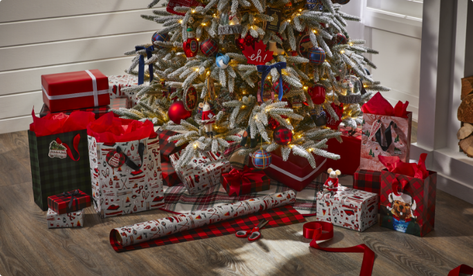 Des rouleaux de papier d’emballage et des cadeaux emballés sous un sapin. 