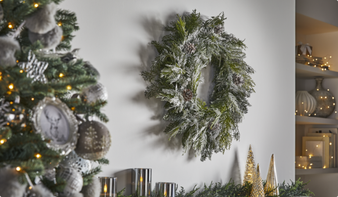 Une couronne de Noël floquée accrochée sur un mur dans un salon.