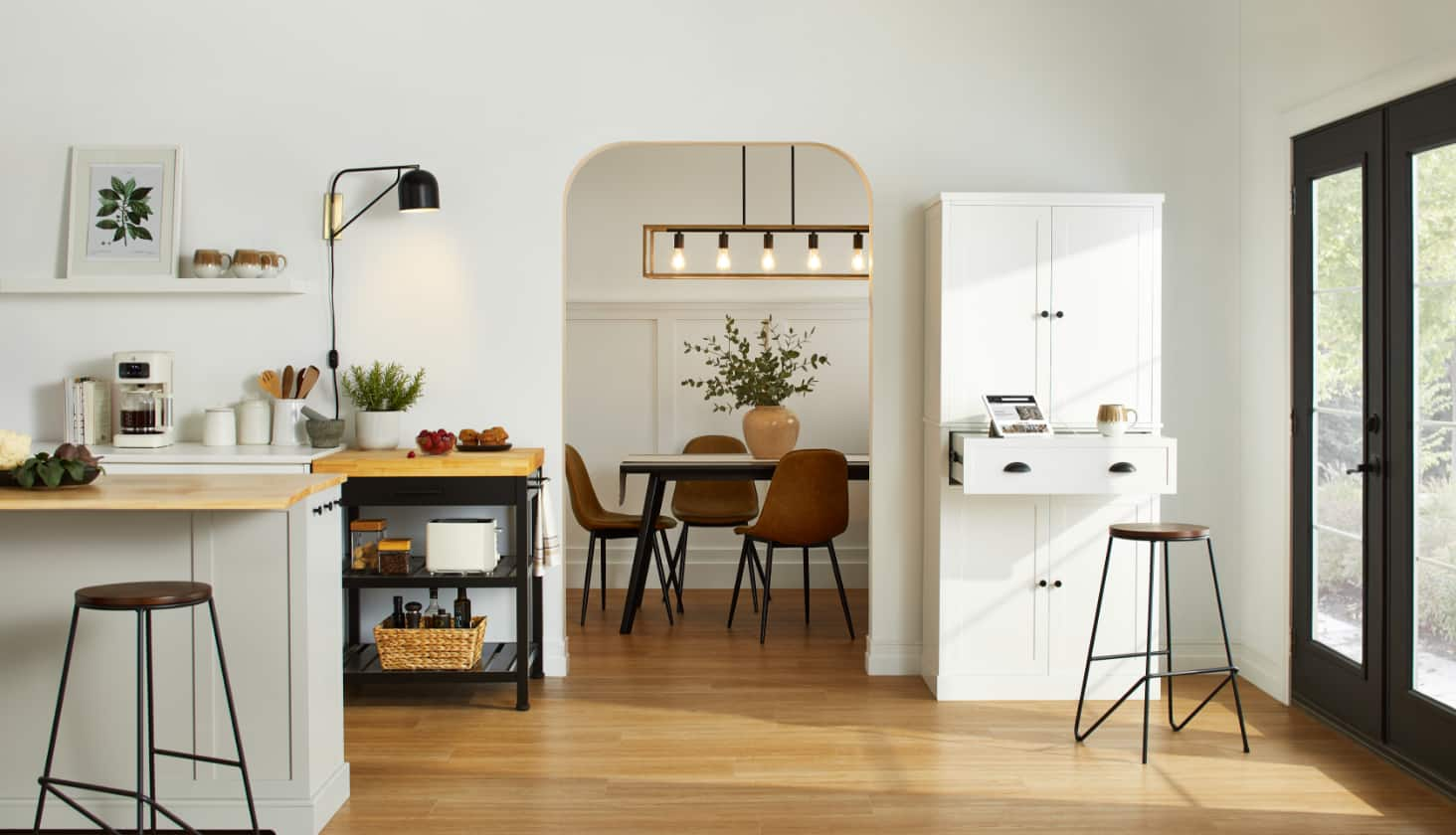 White, black, and brown kitchen with two leather bar stools, white cabinet, and black shelf