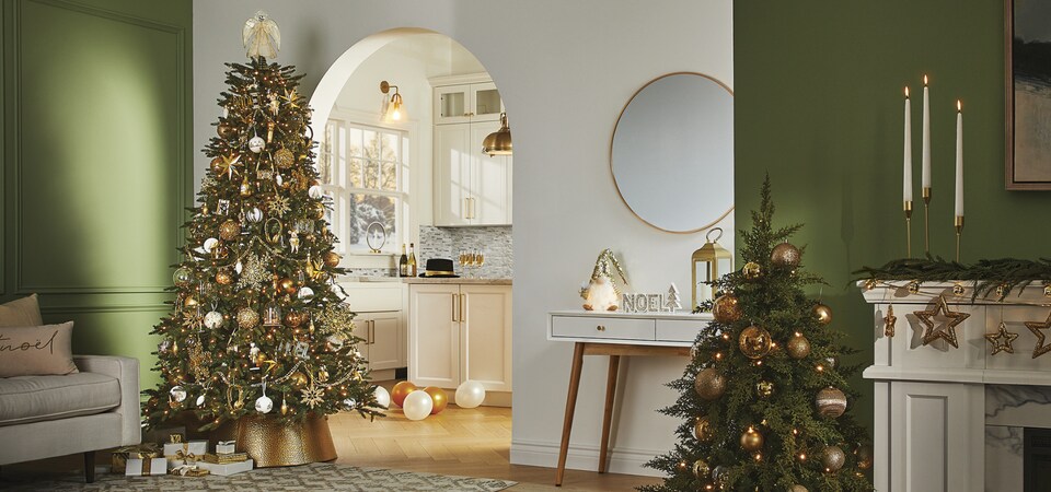 Un salon et un sapin de Noël décorés avec des décorations CANVAS Moments en or. 