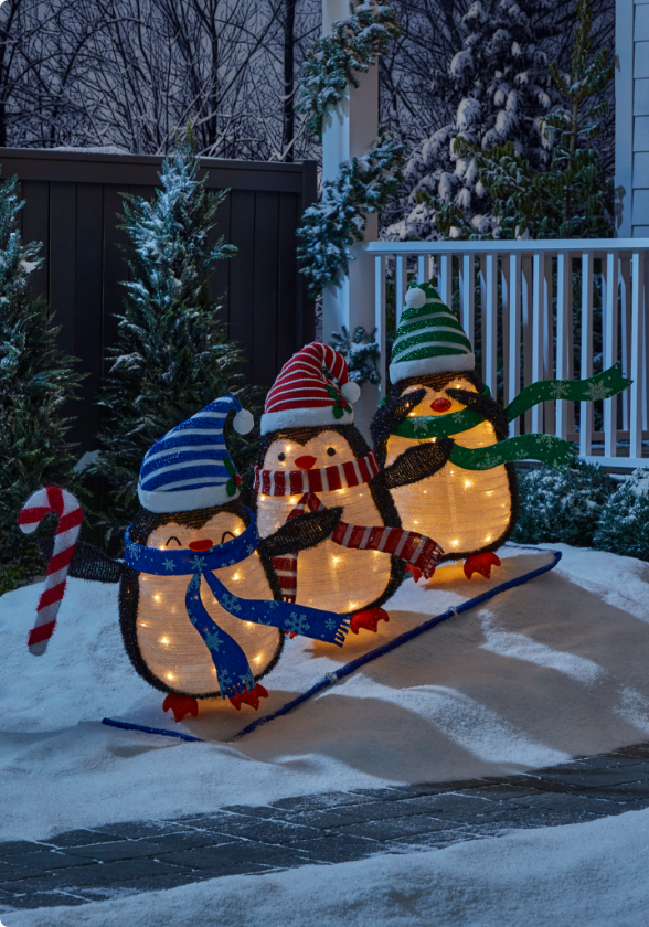 3 pingouins skieurs pliants illuminés CANVAS dans une cour enneigée. 