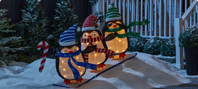 3 pingouins skieurs pliants illuminés CANVAS dans une cour enneigée. 