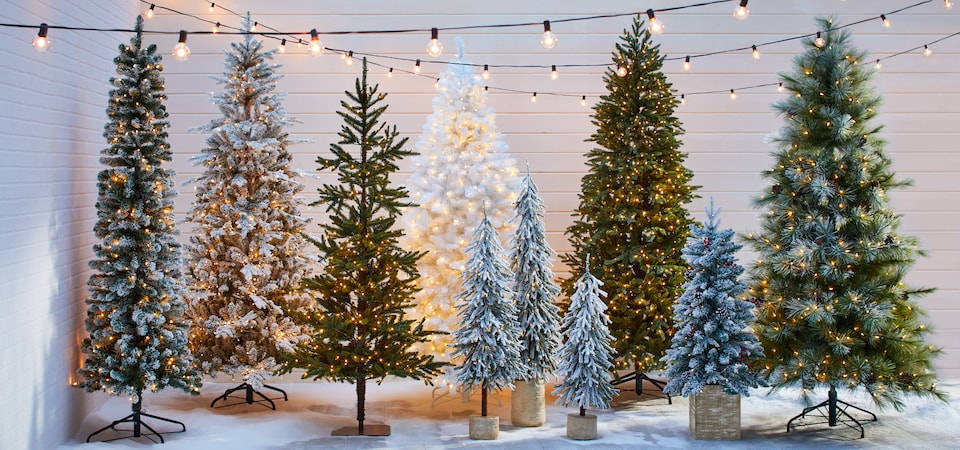 A row of artificial Christmas trees in assorted styles and sizes.