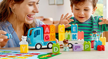A woman and toddler play with a LEGO Alphabet Truck set.
