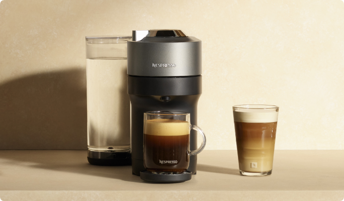 Une cafetière simple Nespresso Vertu Pop+ titane avec deux cafés sur un comptoir de cuisine.