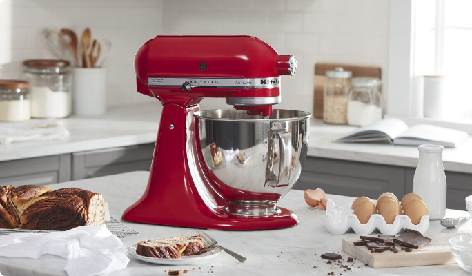 A red KitchenAid Tilt-Head Stand Mixer on a kitchen counter with baking ingredients.