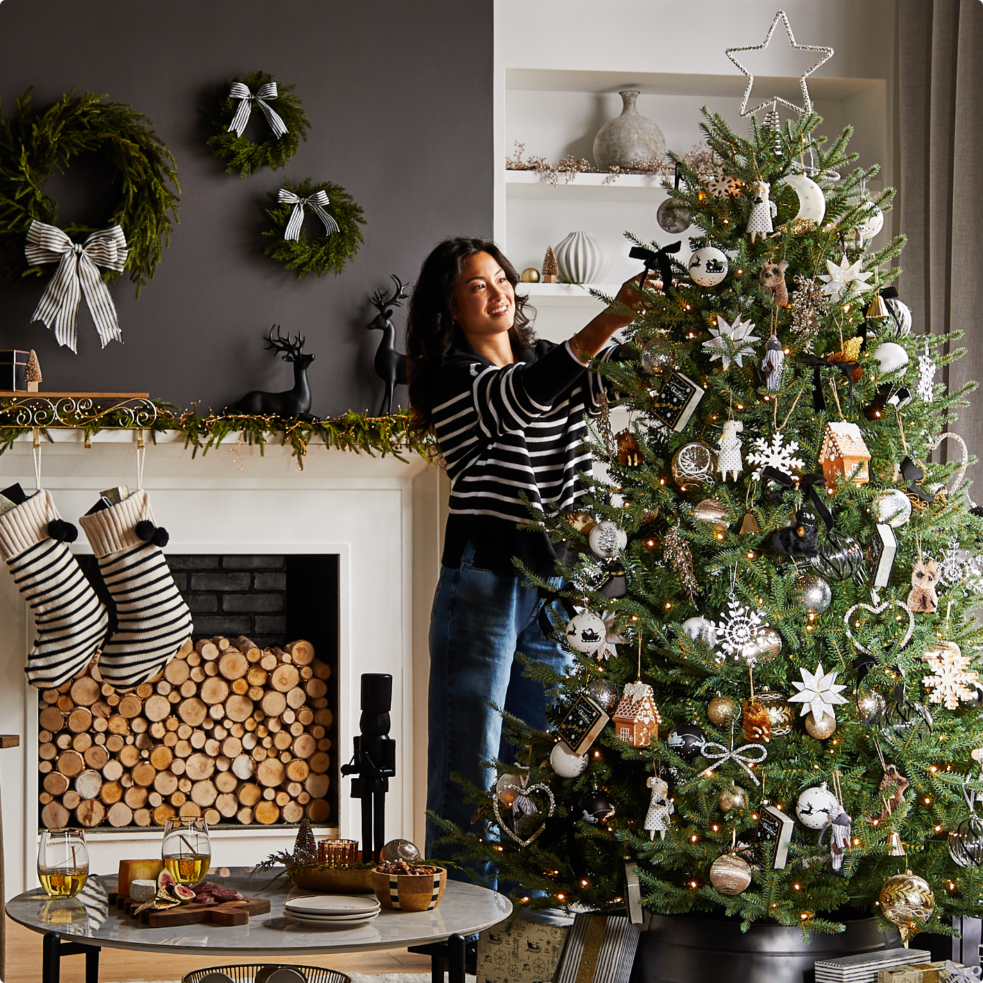 A woman decorating a tree with CANVAS Night Before Christmas ornaments and accessories. 